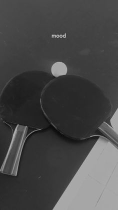 two ping pong paddles sitting on top of a table next to each other