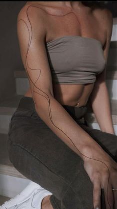 a woman sitting on the floor with her arm tattoo