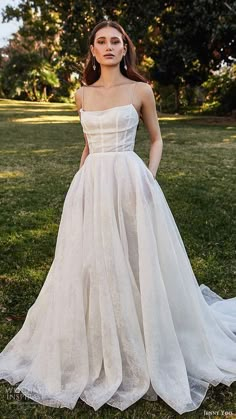 a woman standing in the grass wearing a wedding dress