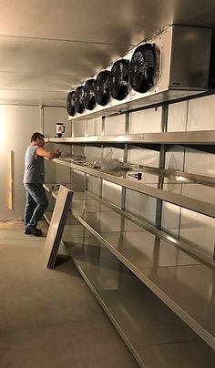 a man standing next to an oven in a kitchen with lots of shelves on the wall