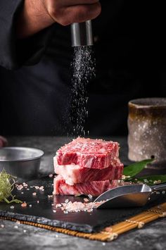 a chef sprinkling seasoning on raw meat