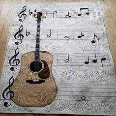 an acoustic guitar sits on top of a quilted placemat with musical notes around it