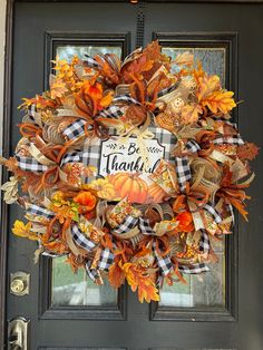 a wreath that says be grateful on it in front of a door with pumpkins and leaves