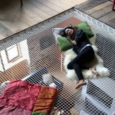 a woman laying on top of a white and green chair next to a dog bed