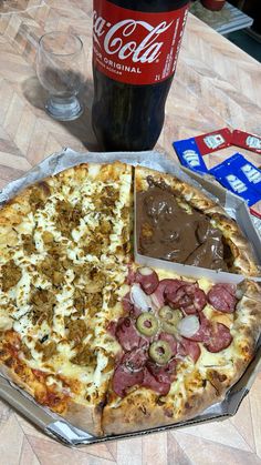 a pizza sitting on top of a pan covered in toppings next to a bottle of coke