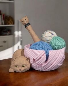 a cat laying on top of a wooden table next to balls of yarn