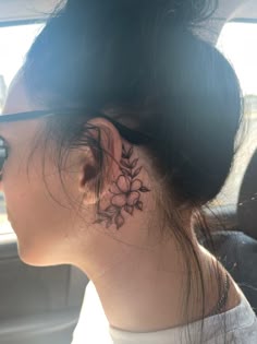 a woman with a flower tattoo on her left side behind the ear is looking out the window