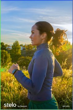 a woman is running in the grass with her hair blowing in the wind and looking off into the distance