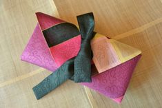 three pieces of fabric folded together on top of each other with ribbons attached to them