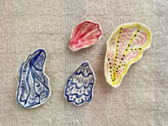 three ceramic bowls with designs on them sitting next to each other in the shape of seashells