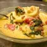 a pasta dish with spinach, ham and cheese in a bowl on a table