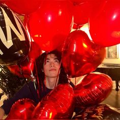 a woman is surrounded by red and black balloons