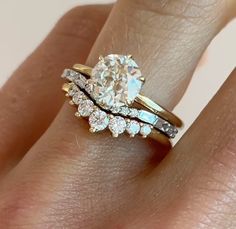 a woman's hand with a diamond ring on top of her finger, and an engagement ring in the middle