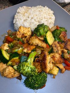 chicken, broccoli, and other vegetables are on a plate with white rice