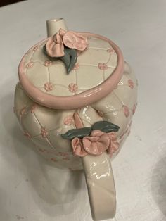 a ceramic teapot with pink flowers on it