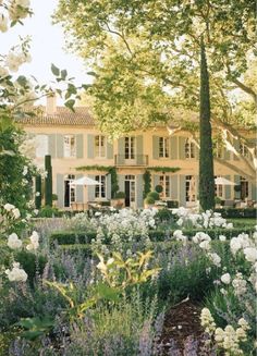 a large white house surrounded by trees and flowers