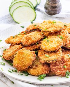 some fried food on a white plate with cucumbers