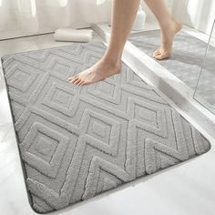 a person standing on a bathroom rug in front of a mirror