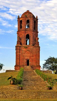 an old brick tower with a bell on top and steps leading up to the bottom