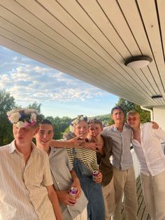 a group of people standing next to each other on a porch under a white awning