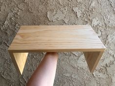 a person's arm is holding a wooden table