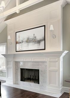 a living room with a white fireplace and large painting on the wall over it's mantle