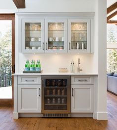 a kitchen with white cabinets and wood flooring next to a window that looks out onto the outdoors