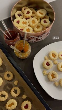 some cookies and jam are on a tray next to a bowl with jelly in it