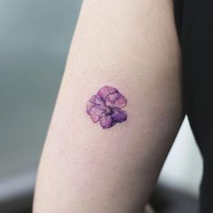 a small purple flower tattoo on the right arm