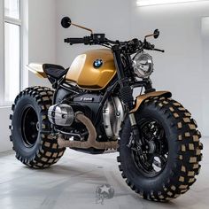 a gold and black motorcycle is parked in a room with large tires on the front