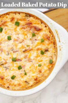 a baked potato dip in a white casserole dish with green onions and cheese