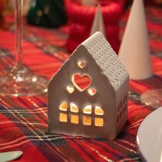 a house shaped candle holder sitting on top of a table next to plates and wine glasses