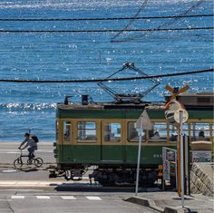 a person riding a bike on the street next to a green and yellow trolley car