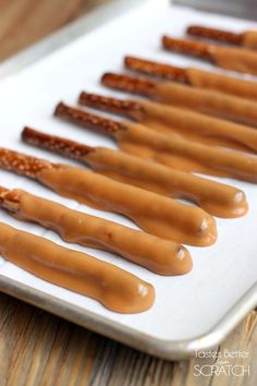 there are many hot dogs on the pan ready to be cooked and drizzled with caramel sauce