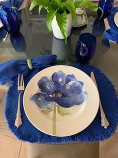 a blue flower on a white plate with silverware