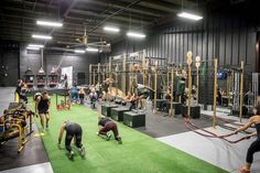 people doing exercises in an indoor gym with ropes and ladders on the floor, while others watch