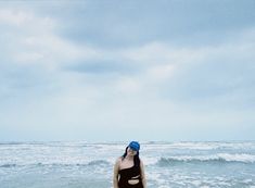 a woman in a bathing suit standing on the beach with her surfboard under her arm