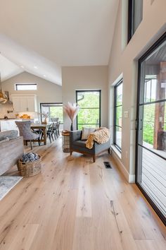 a living room filled with furniture next to a large open window on top of a hard wood floor