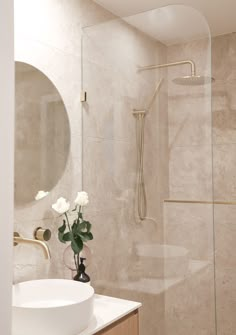 a white sink sitting under a bathroom mirror next to a shower