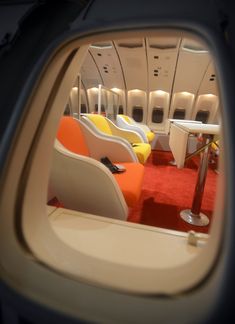 the inside of an airplane with chairs and tables in it's rear view mirror