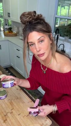 a woman standing at a kitchen counter with food in front of her