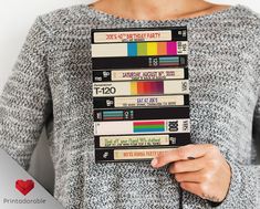 a woman holding a stack of cassettes in her hands with a pink heart on the side