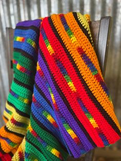 a multicolored crocheted blanket sitting on top of a wooden chair