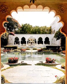 an outdoor garden with flowers and water features in the foreground, surrounded by arches