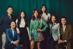 a group of people standing next to each other in front of a green wall with curtains