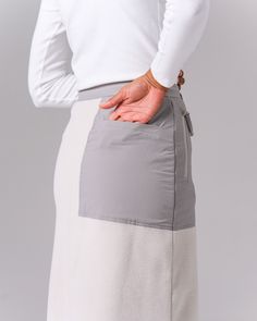 The Double Face Fleece Skirt is a thick, lightweight fleece bottom. The skirt is made from Polartec 200 Series Fleece, with stretchable polyester panels on the face and lining. The skirt features an A-line design, button and zipper closure at the front, stretchable sections through the waist and hip, two zippered pockets at the waist, and a zippered back pocket. Fleece Skirt, Double Face, Line Design, Back Pocket, Zipper, Skirt, Grey, Design