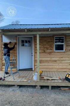 a person standing on a ladder in front of a small wooden house with siding being installed