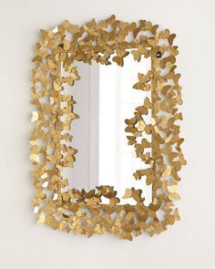 a mirror that is on the wall with gold foil leaves around it and a white background