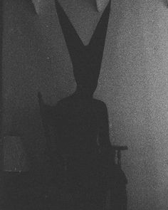 black and white photograph of a person sitting in a chair with their back turned to the camera