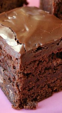 a close up of a piece of cake on a pink plate with chocolate frosting